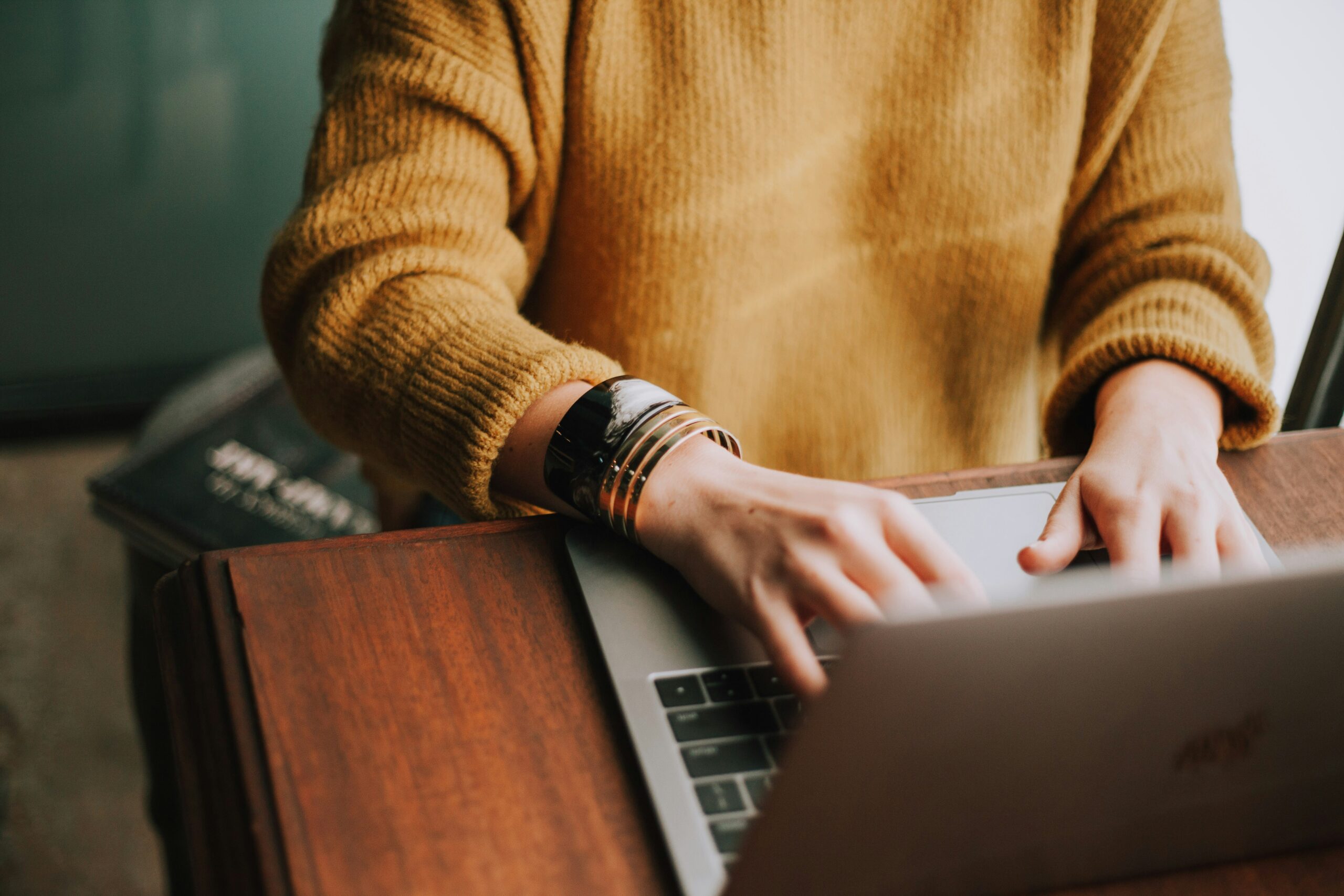 person in yellow sweater typing on laptop