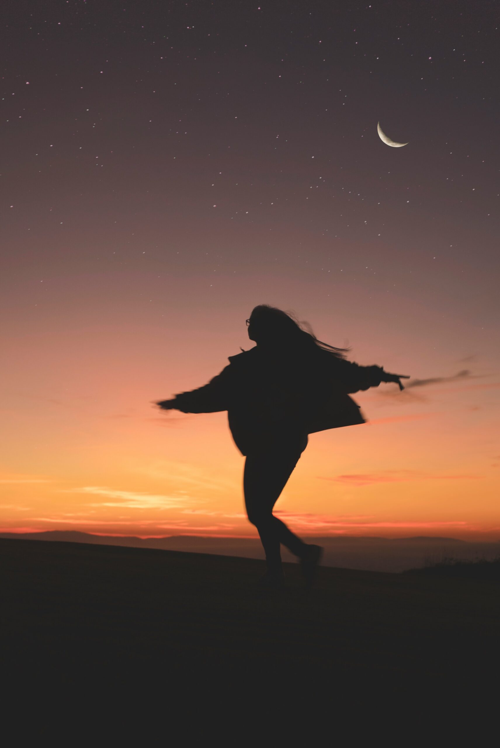 sillouhette of a person moving under the moon at dusk